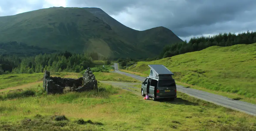 Campervan am Wegrand auf der Isle of Mull mit grüner Wiese und Berg im Hintergrund